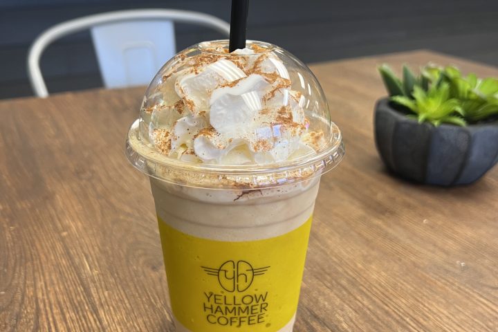 Iced coffee with whipped cream and caramel on a wooden table.