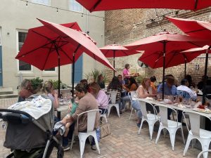 a group of people sitting at a table with an umbrella