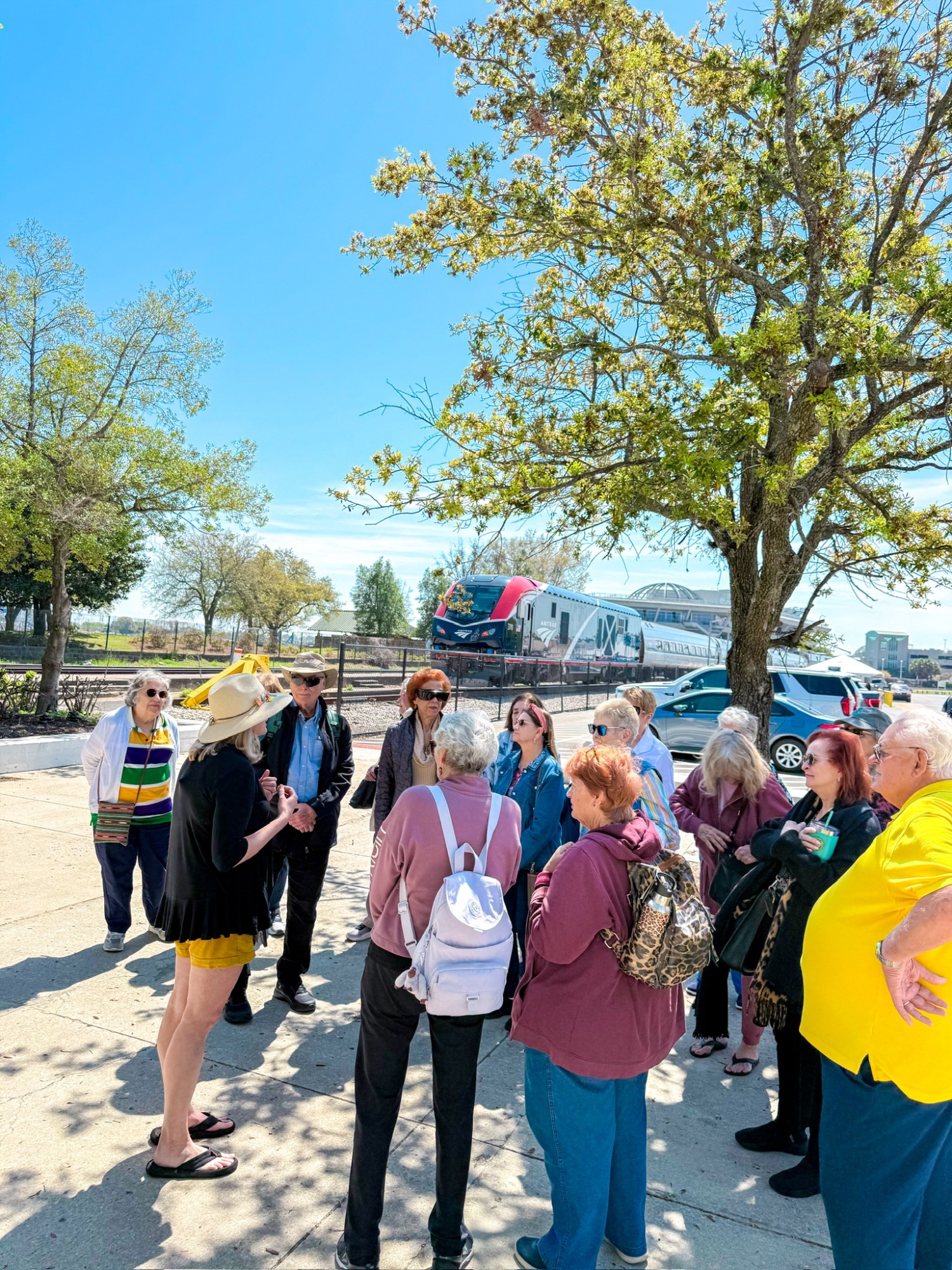 A group of people gathered outdoors near a bus on a sunny day.